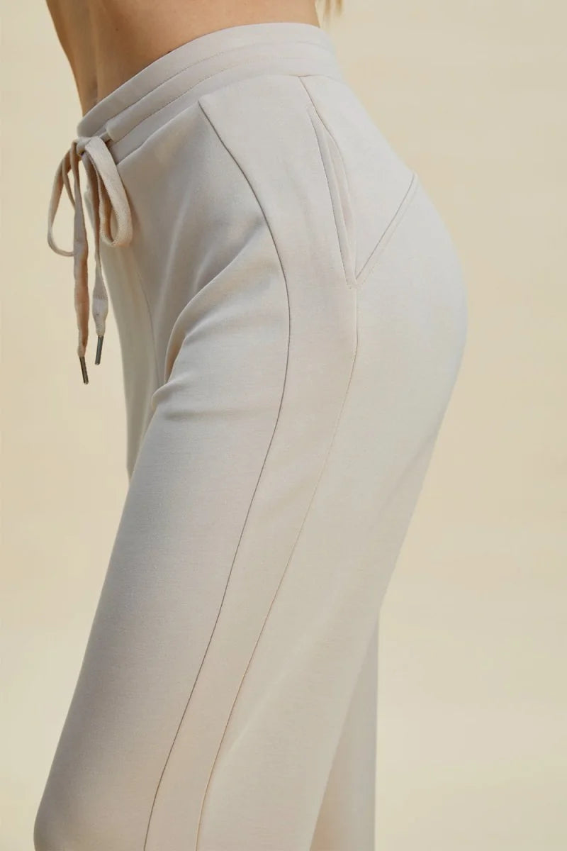 Close-up of beige knit sweatpants featuring a drawstring waist and side pocket detail.