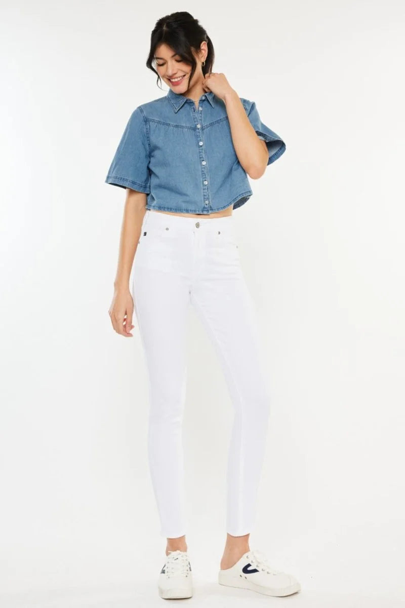 Full-length shot of a woman wearing white skinny jeans and a denim crop top.