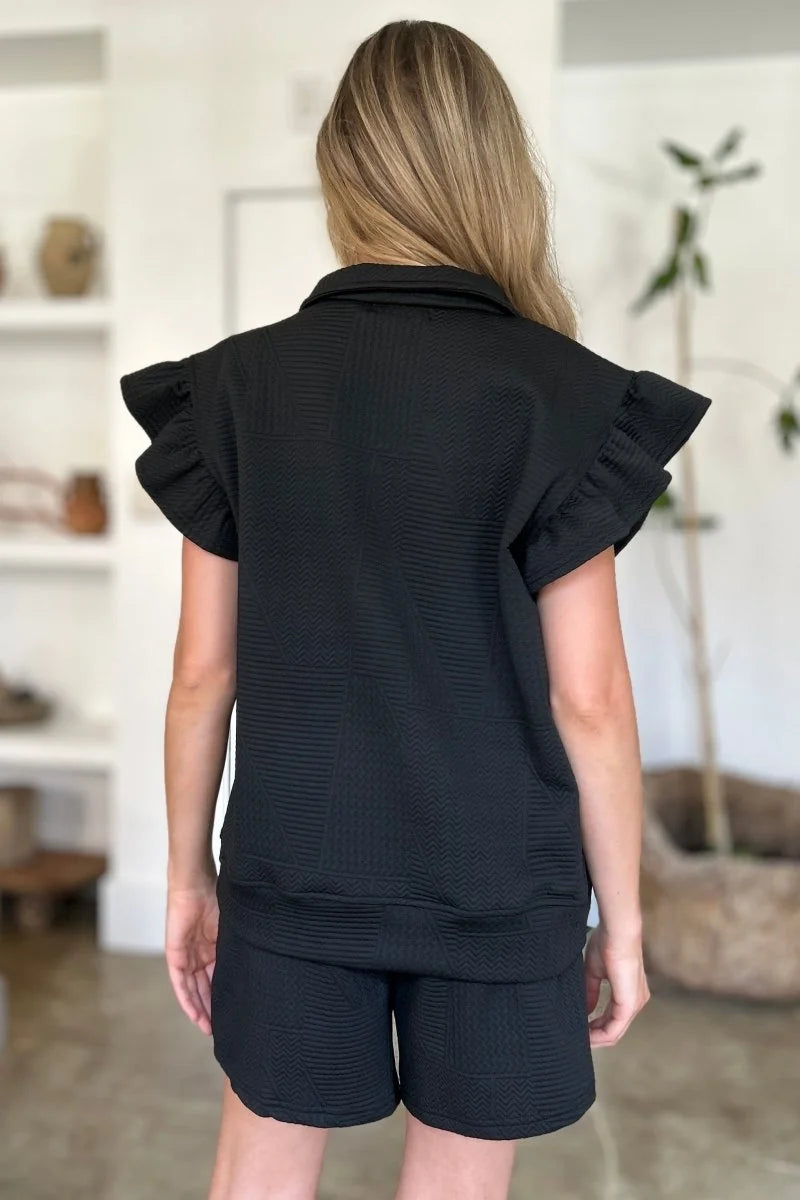 Black quilted short suit with ruffled cap sleeves, shown from the back.