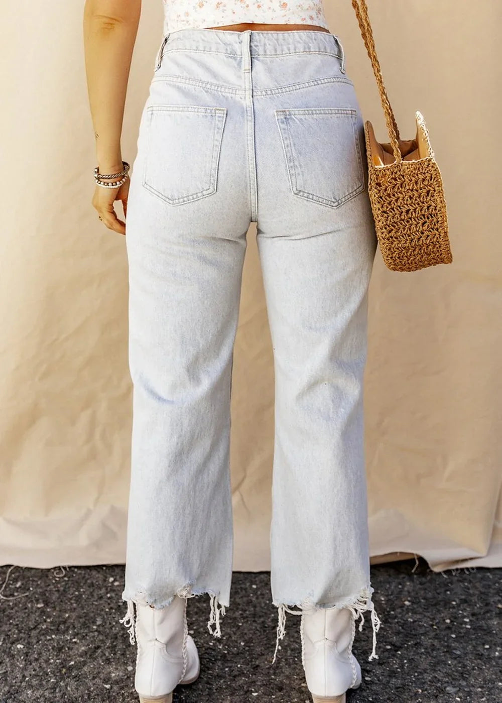 Light wash denim jeans with a frayed hem and a regular fit, shown from the back.
