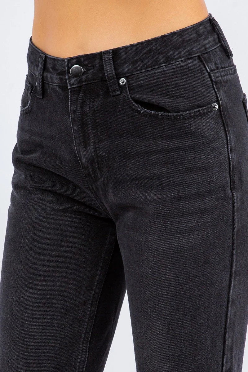 Close-up of black high-waisted denim jeans with a button closure and pocket detail.