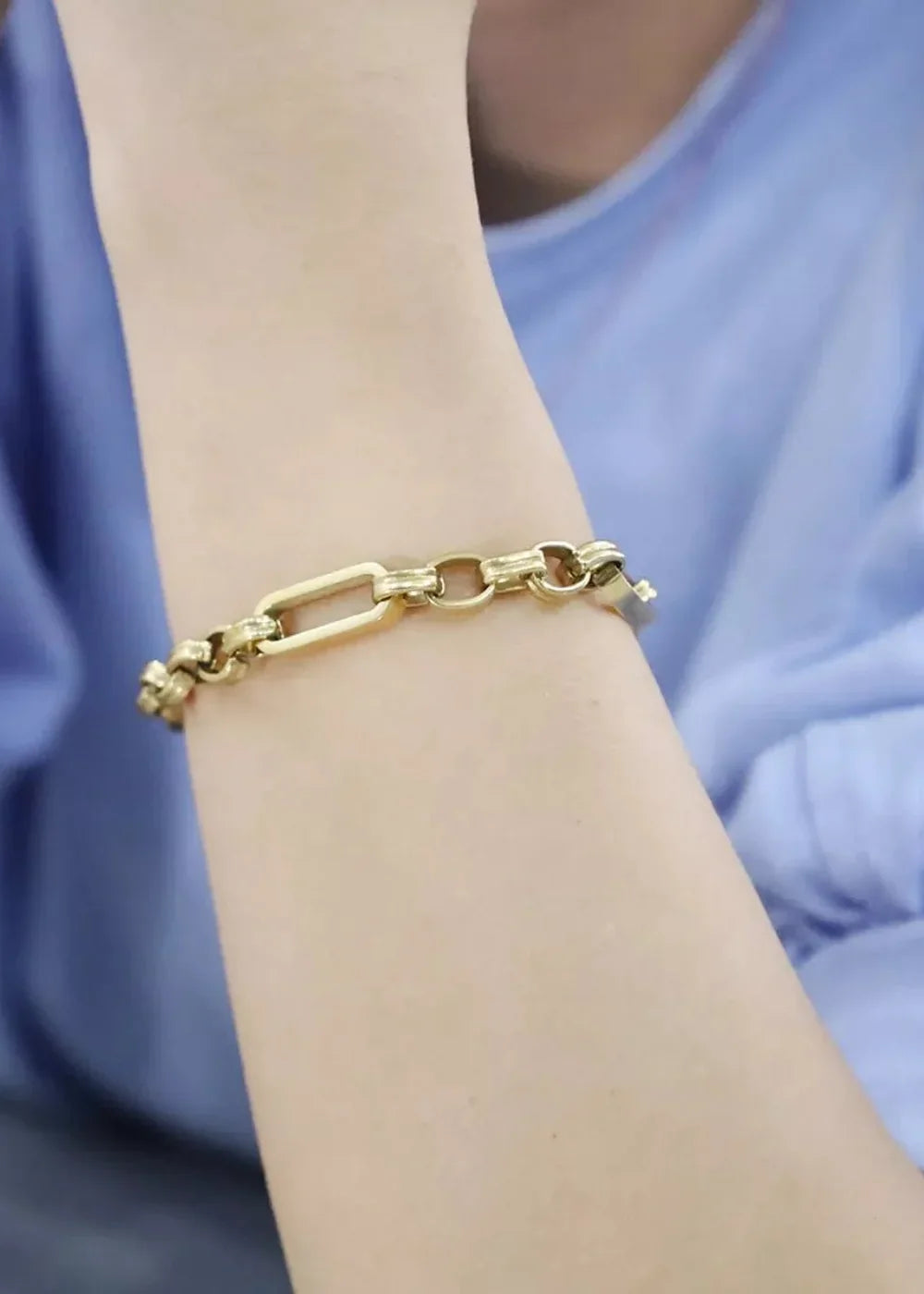 Gold-plated chain bracelet with mixed link styles on an arm