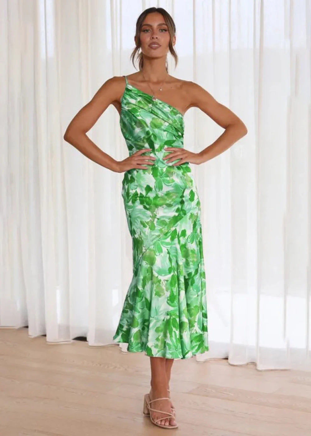 Green floral print one-shoulder midi dress with a draped bodice and flowing skirt.