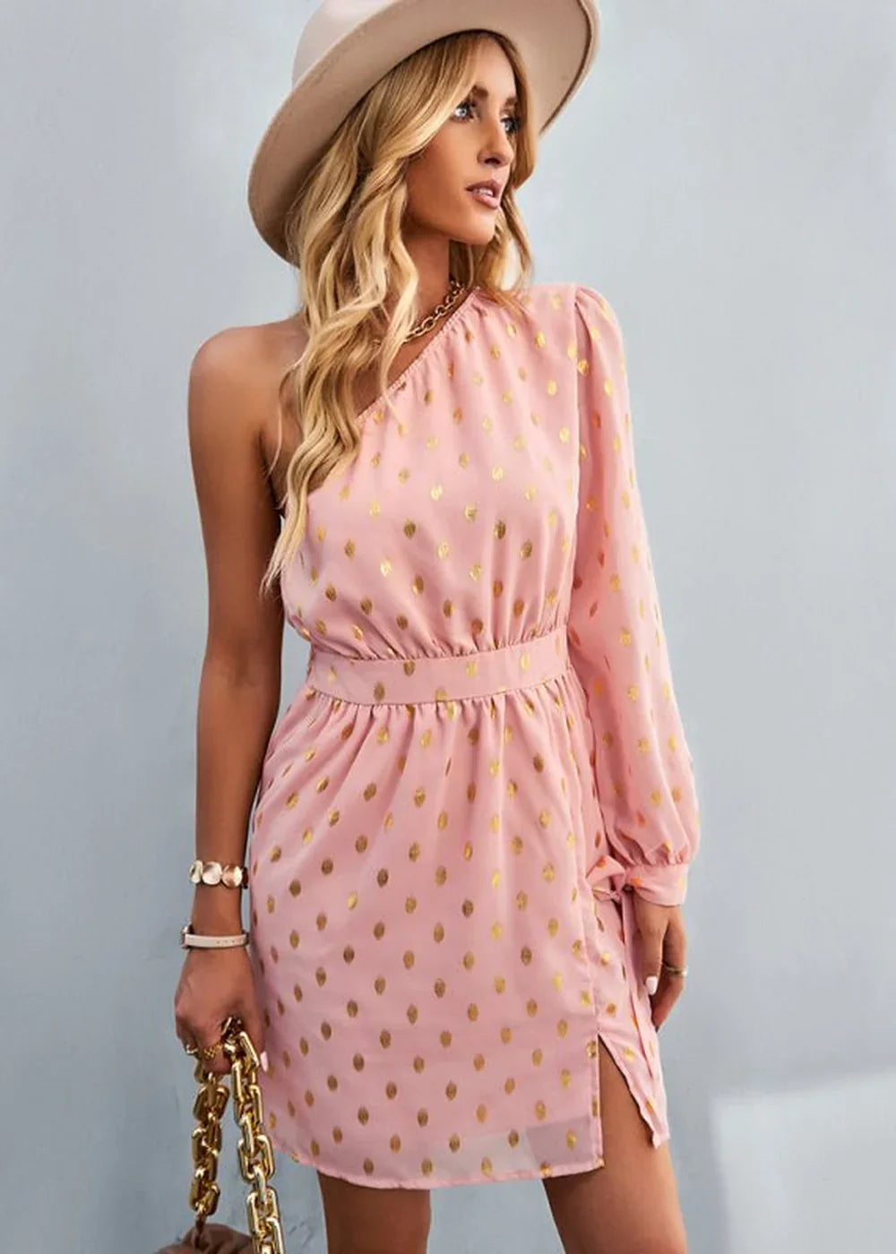 Pink one-shoulder mini dress with gold polka dots and a side slit.