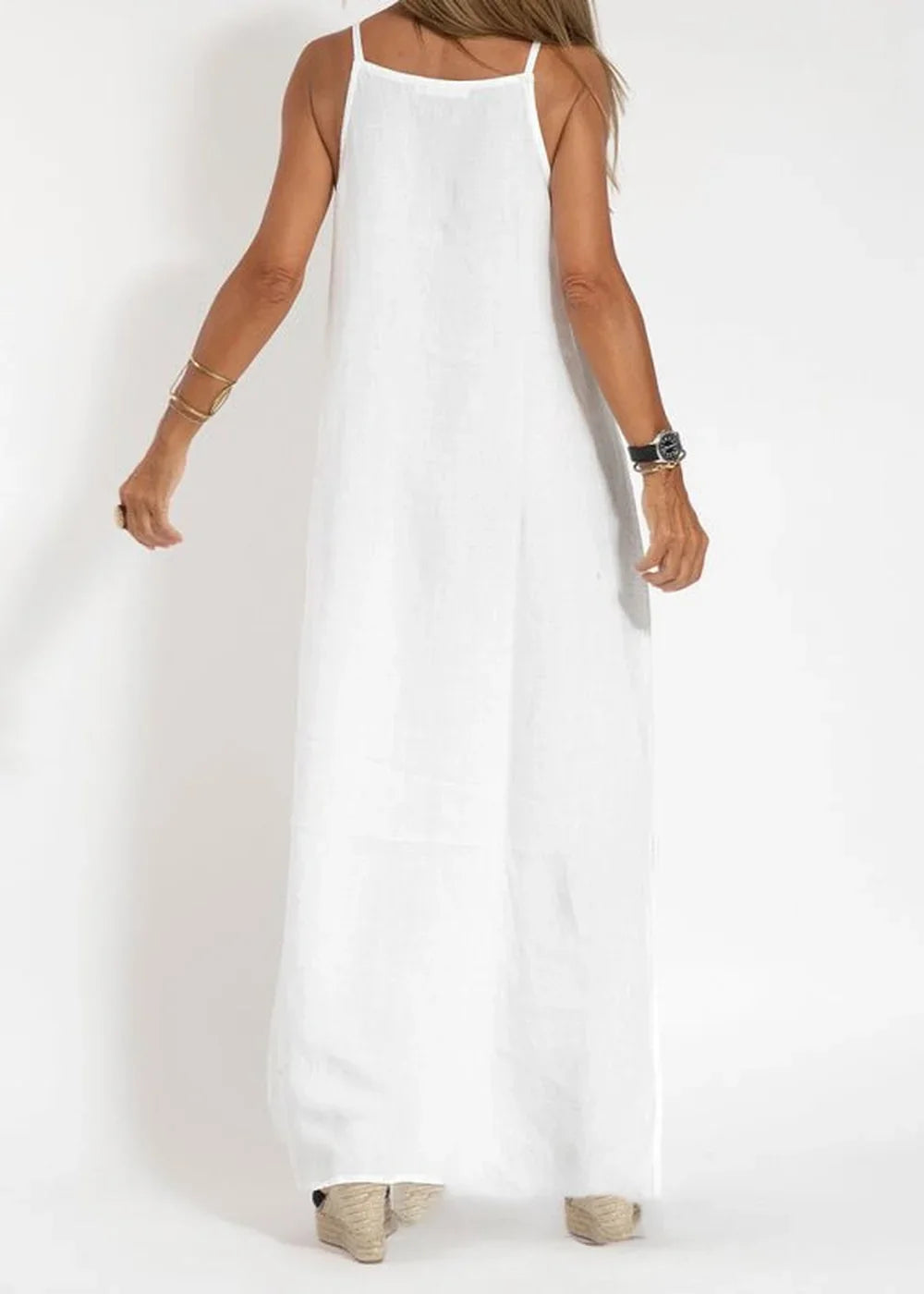 White linen-blend maxi dress with spaghetti straps, worn with wedge sandals.