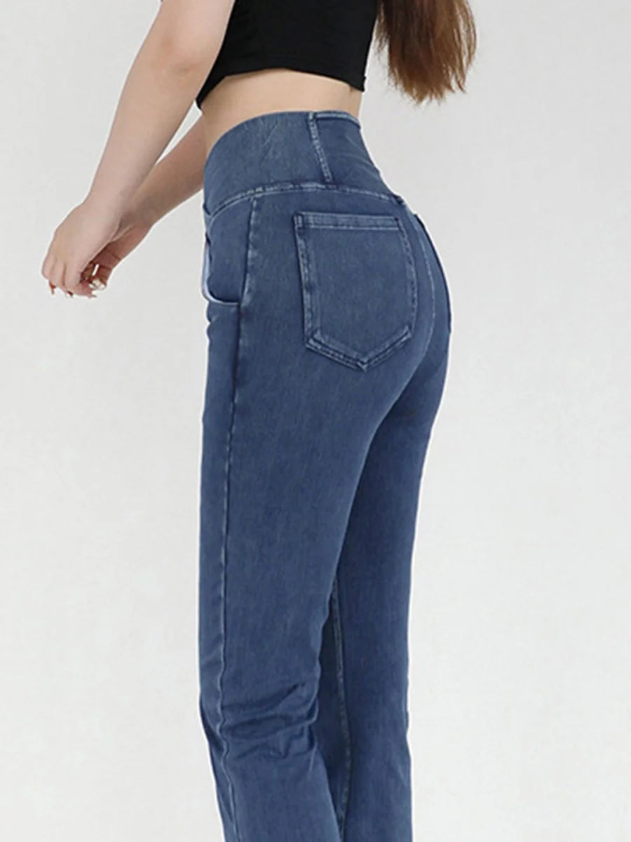 Close-up of a woman wearing high-waisted, dark blue denim jeans with a regular fit.