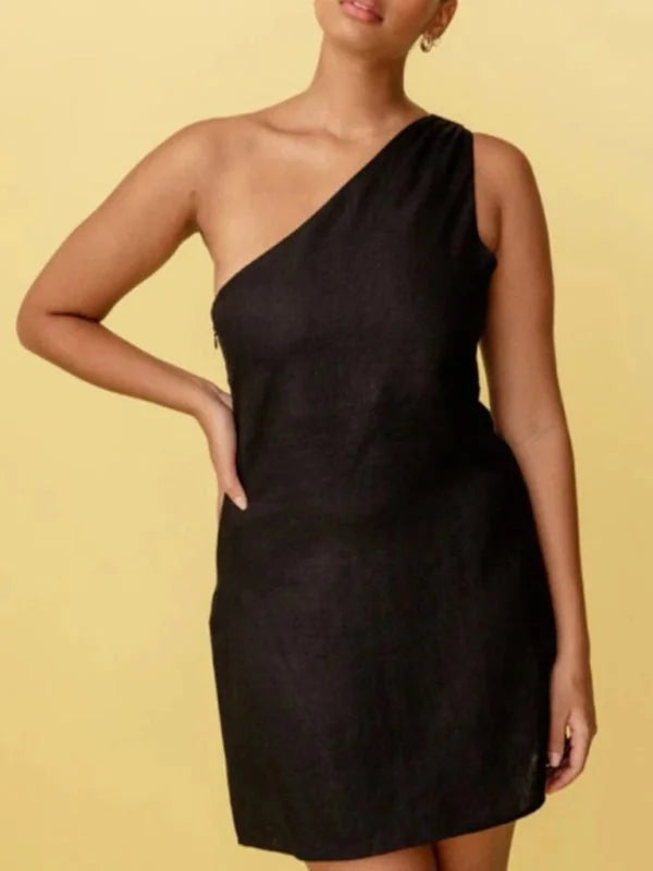 Black one-shoulder mini dress with a textured fabric, shown on a model against a yellow background.