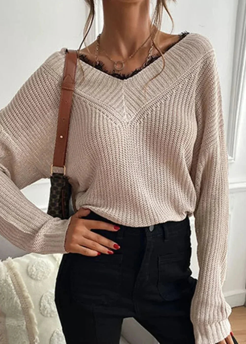 Cream ribbed v-neck sweater with black lace trim, worn by a model.