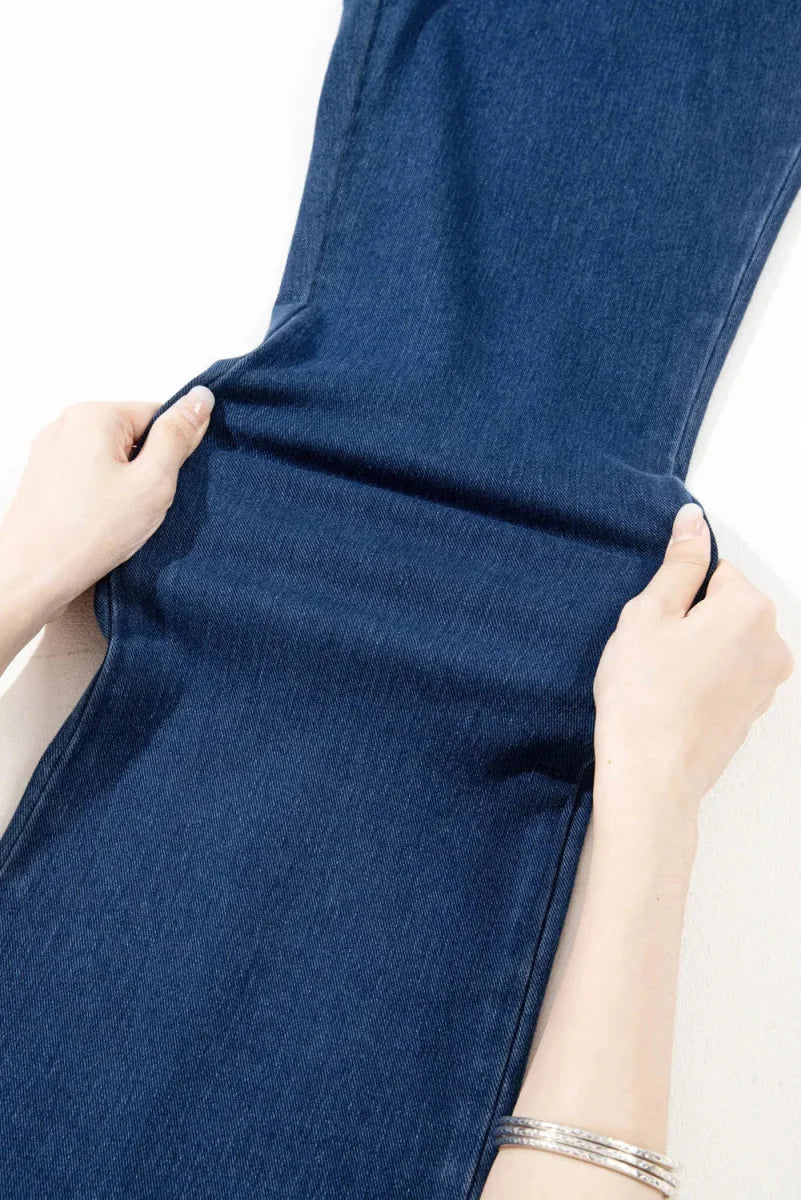 Close-up of navy blue denim pants being stretched to show flexibility.