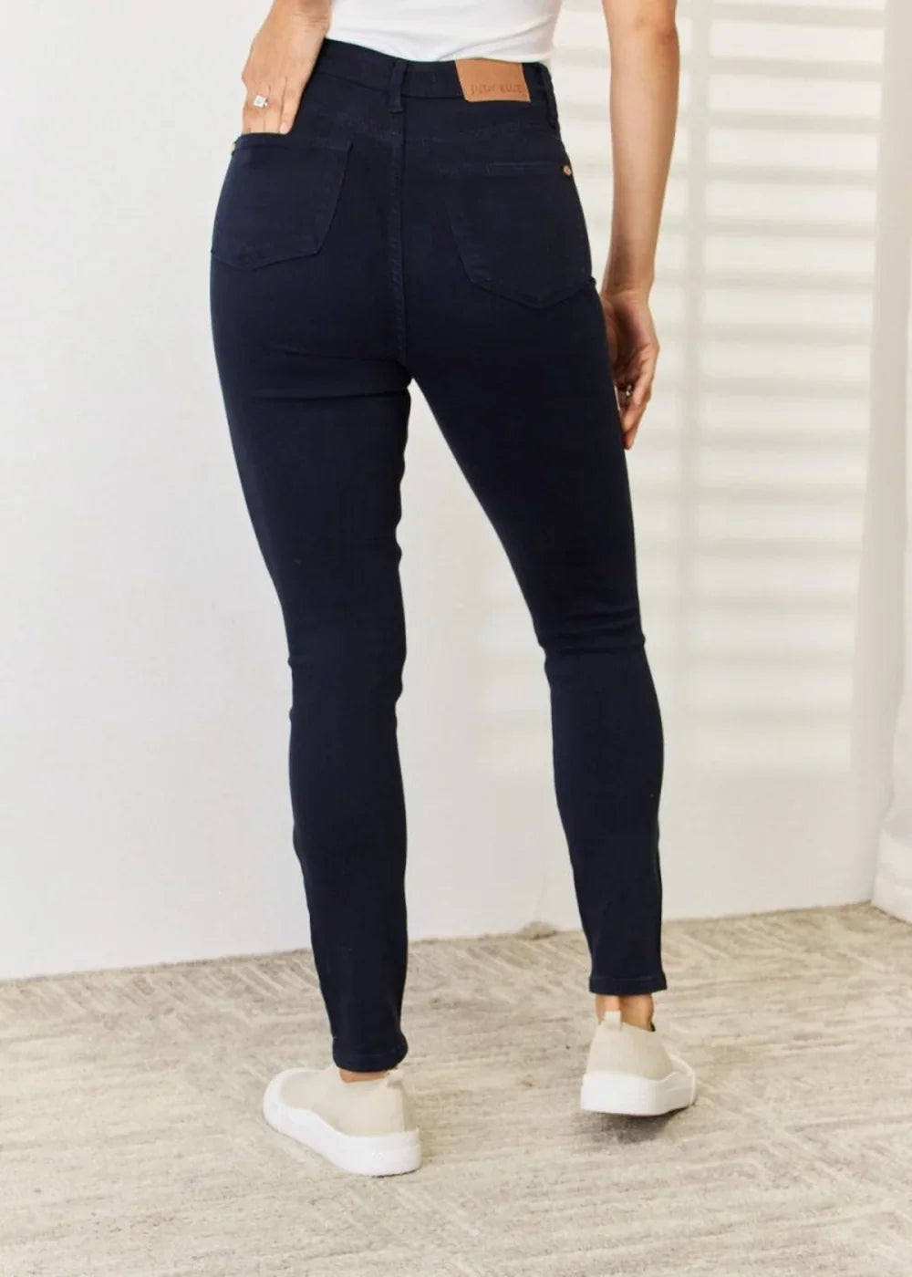 Navy blue skinny jeans with a regular fit, shown from the back on a model.