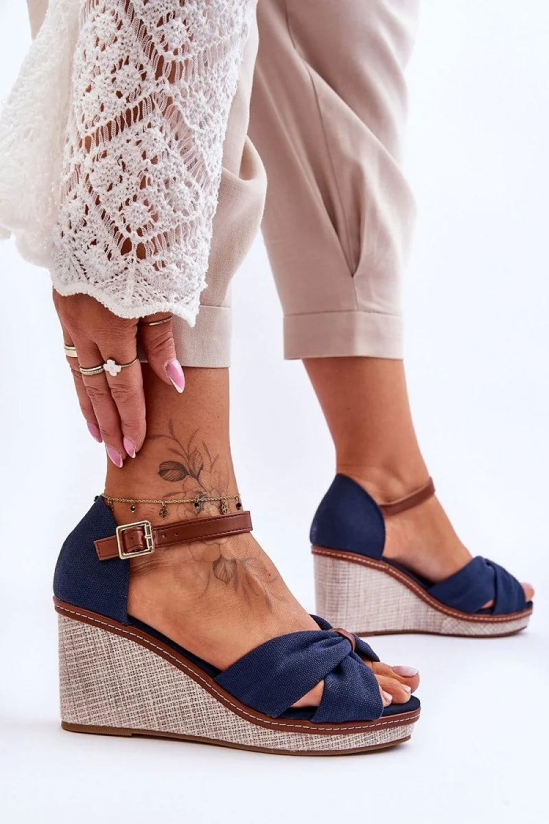 Navy blue fabric wedge sandals with brown ankle strap and woven espadrille sole.