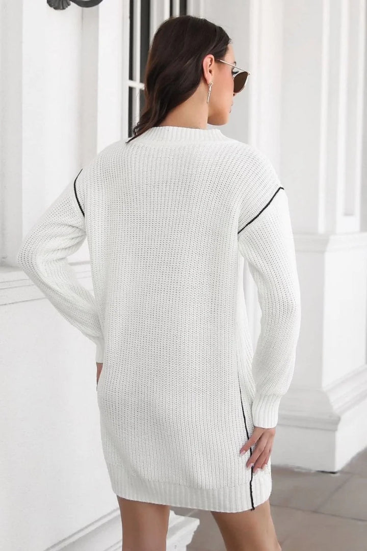 White acrylic knit sweater dress with black trim, seen from the back on a model.