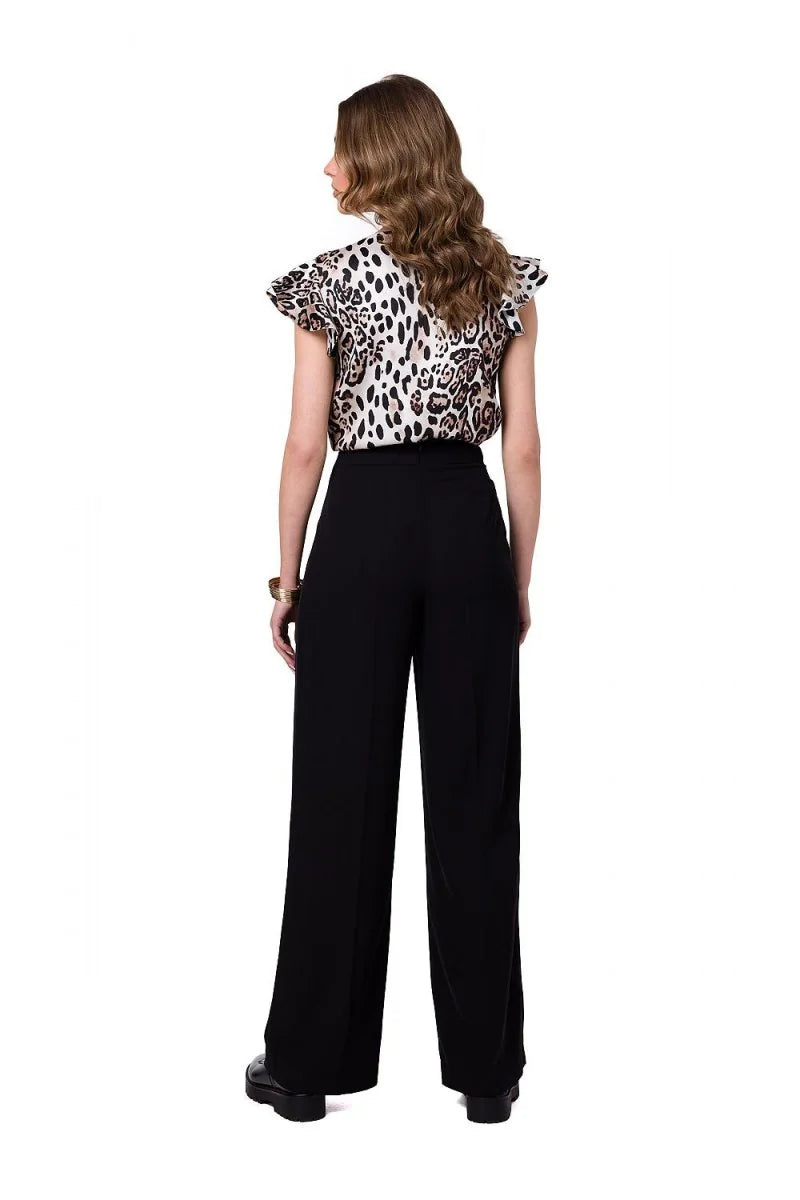 Woman from back in black wide-leg pants and a leopard print top with ruffled sleeves.