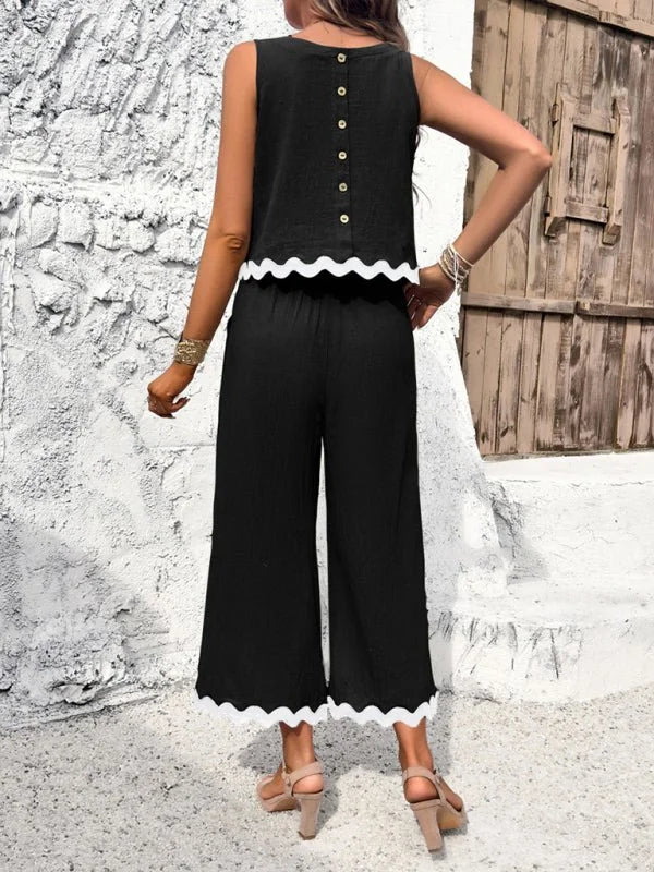 Black wide-leg cropped pants and matching sleeveless top with white scalloped trim, on model.