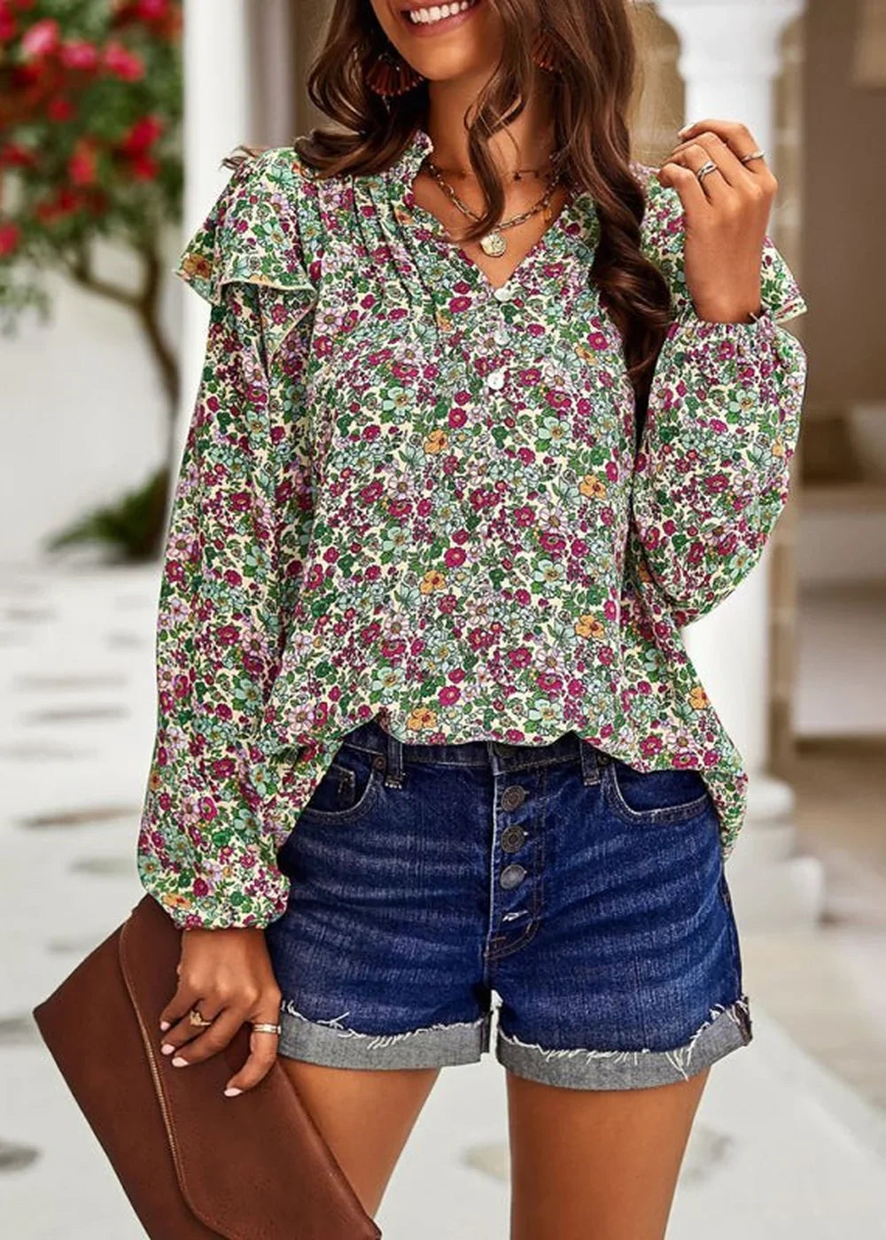 Woman in a floral print blouse with ruffled neckline and sleeves, paired with dark wash denim shorts.