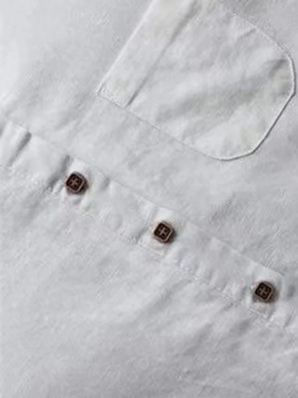 Close-up of a white linen shirt showing three wooden buttons and a chest pocket detail.