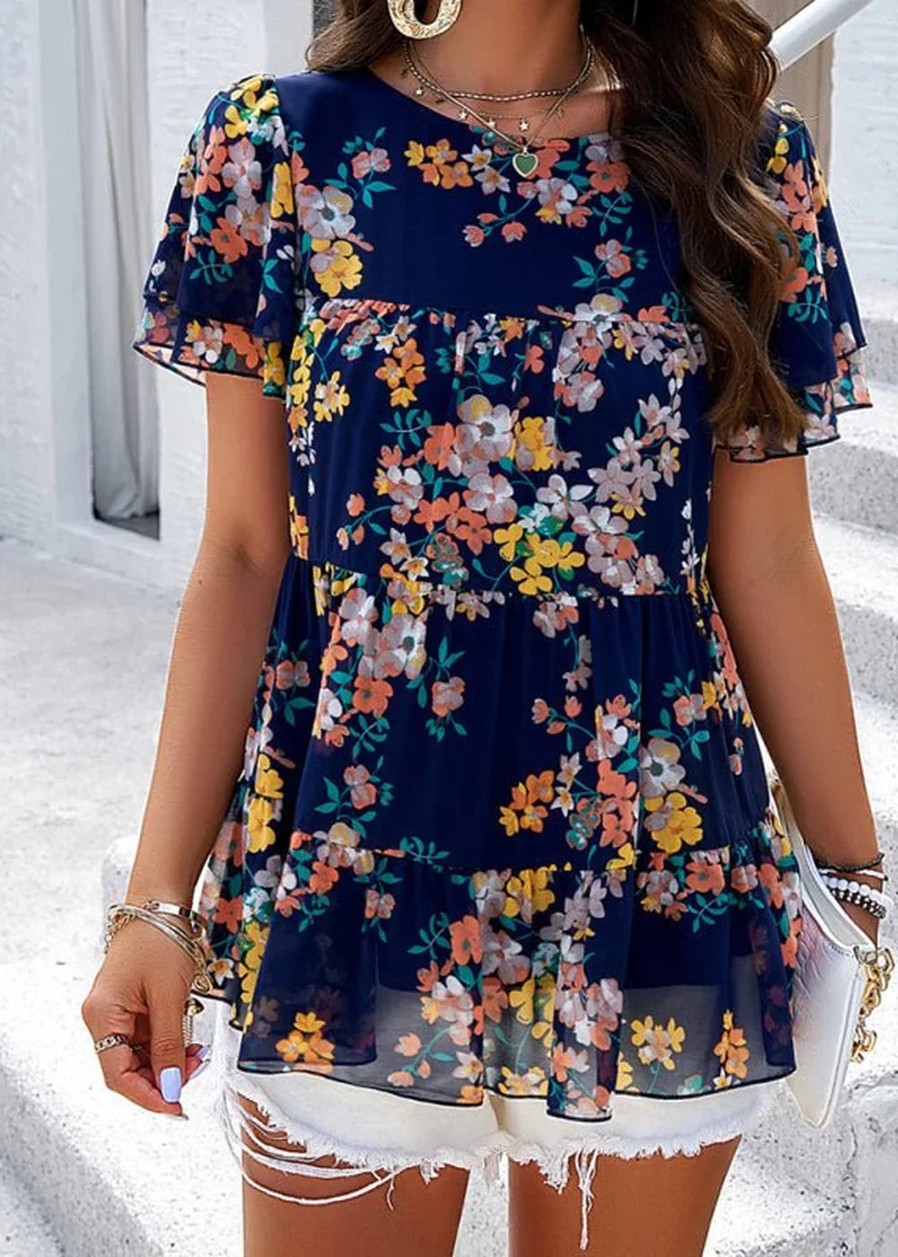 Navy chiffon top with a colorful floral print and tiered ruffled hem.