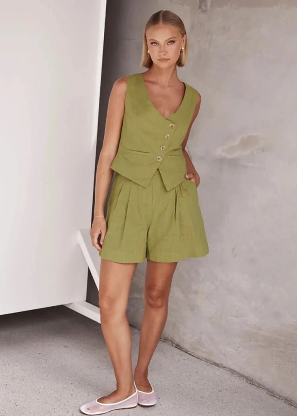 Lime green linen-blend vest and pleated shorts set on a model, with button details.