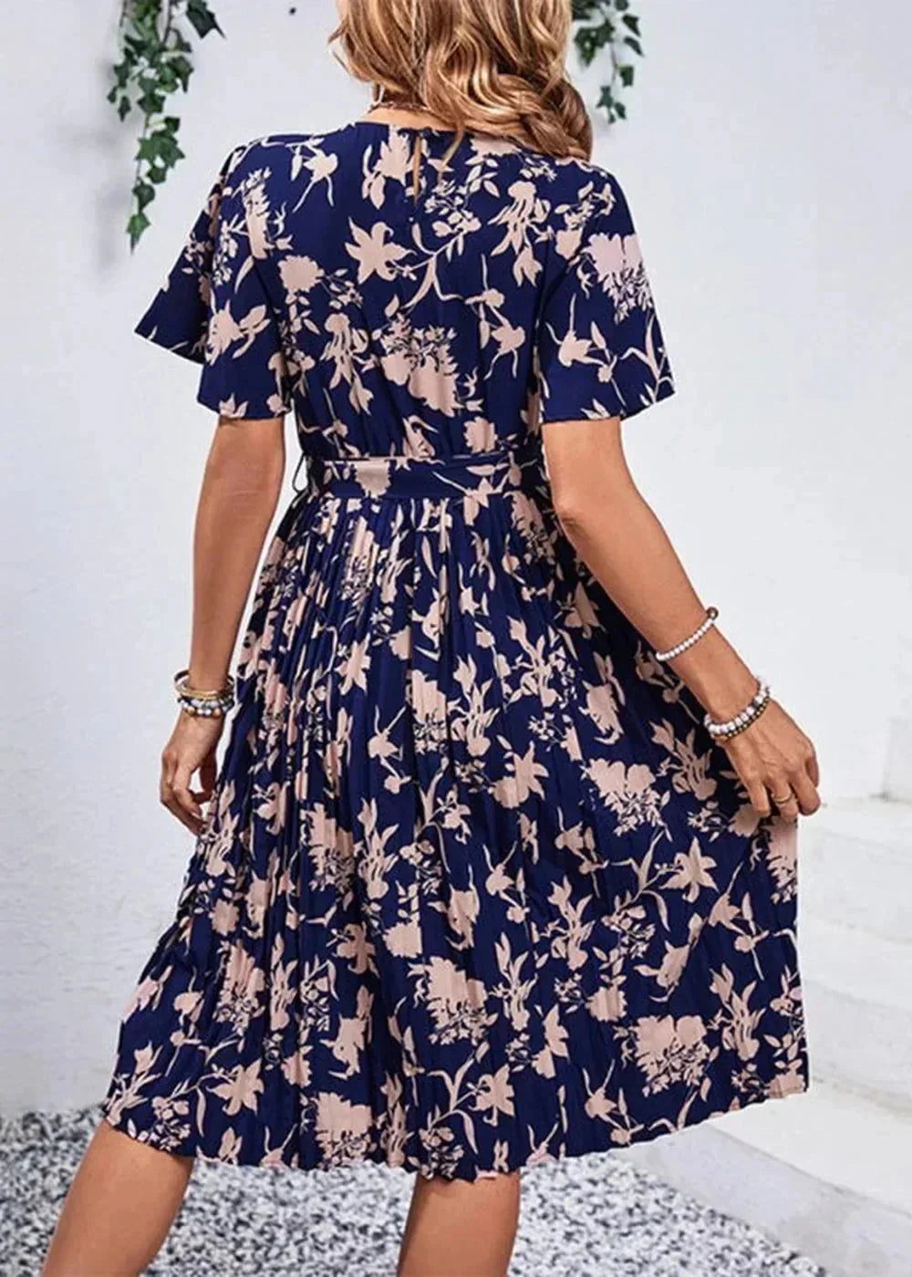 Navy blue midi dress with a light pink floral print, short flutter sleeves, and a pleated skirt.