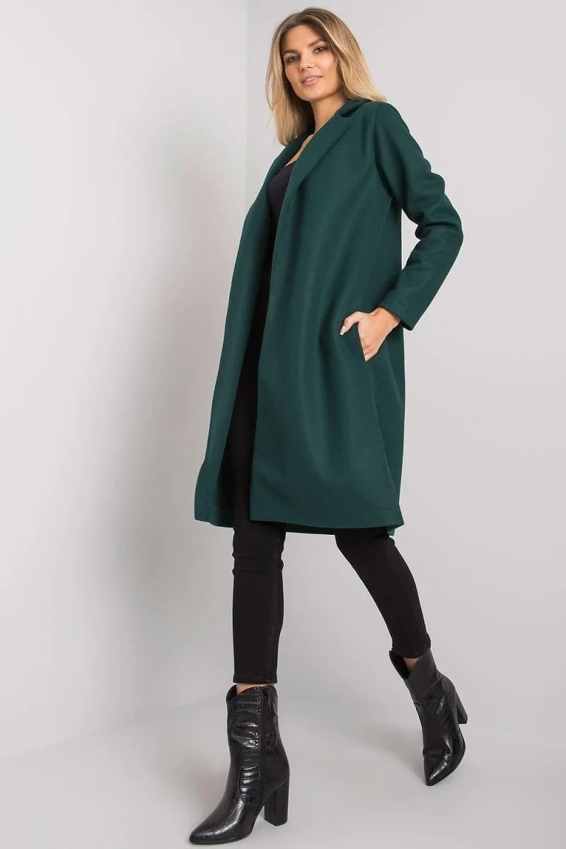 Woman in a dark green coat with black pants and shiny black boots.