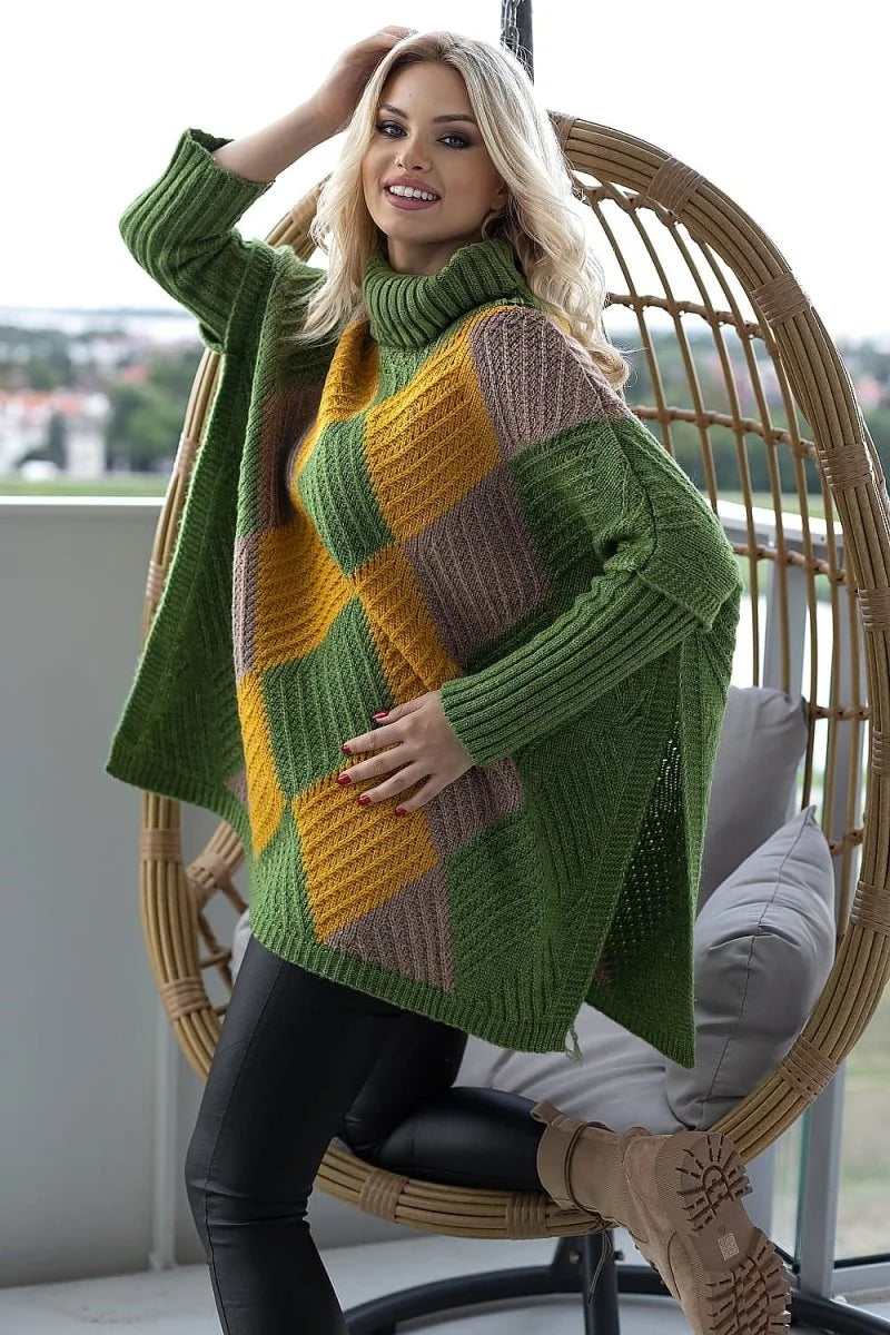 Green, mustard, and taupe checkered knit poncho with a turtleneck, on a woman sitting in a rattan chair.