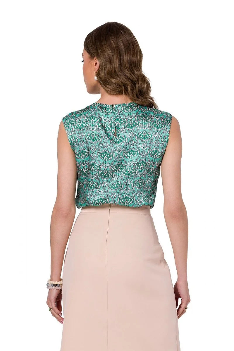 Green sleeveless top with an intricate damask print, paired with a light beige skirt.