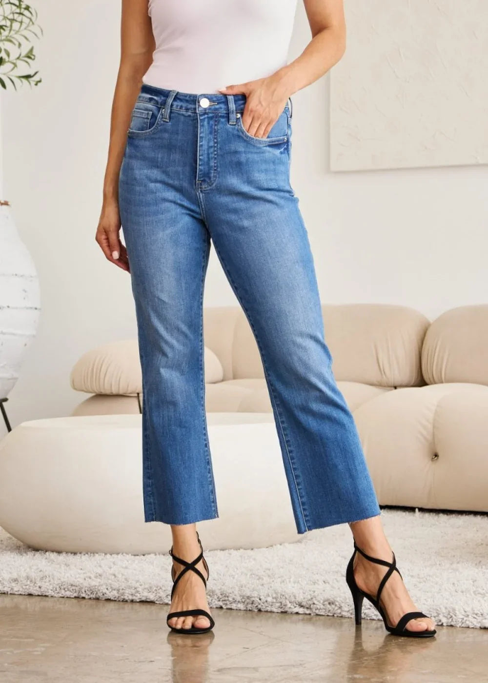 Medium wash denim jeans with a frayed hem and a straight leg fit, worn by a model.