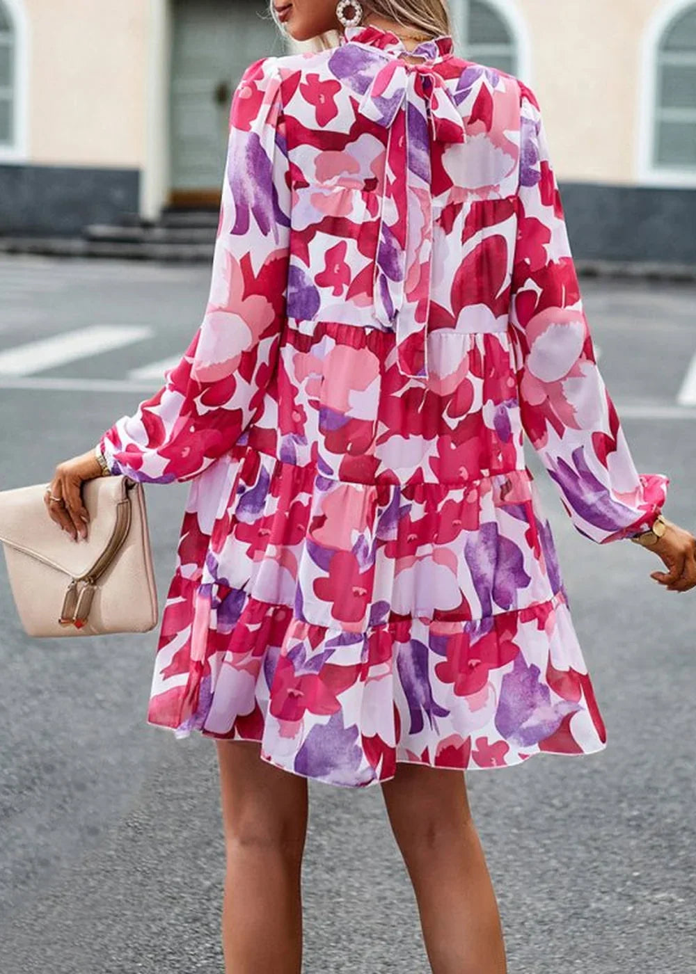 Tiered A-line dress with a vibrant pink, purple, and white abstract floral print and a tie-neck detail.