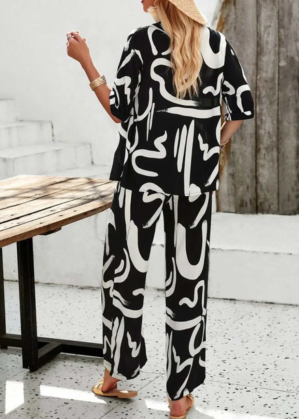 Woman in a black and white abstract print viscose pant suit, back view.