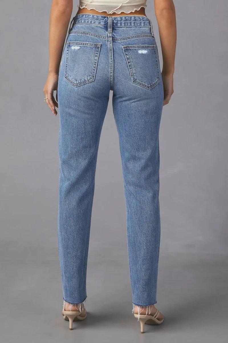 Distressed light wash denim jeans with a frayed hem, shown from the back on a model.