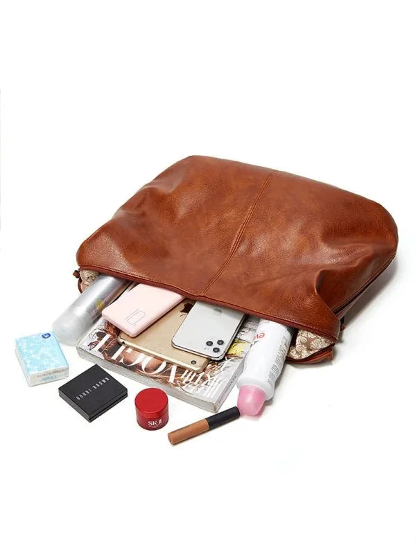 Brown faux leather tote bag with contents including tissues, makeup, phones, and a magazine.