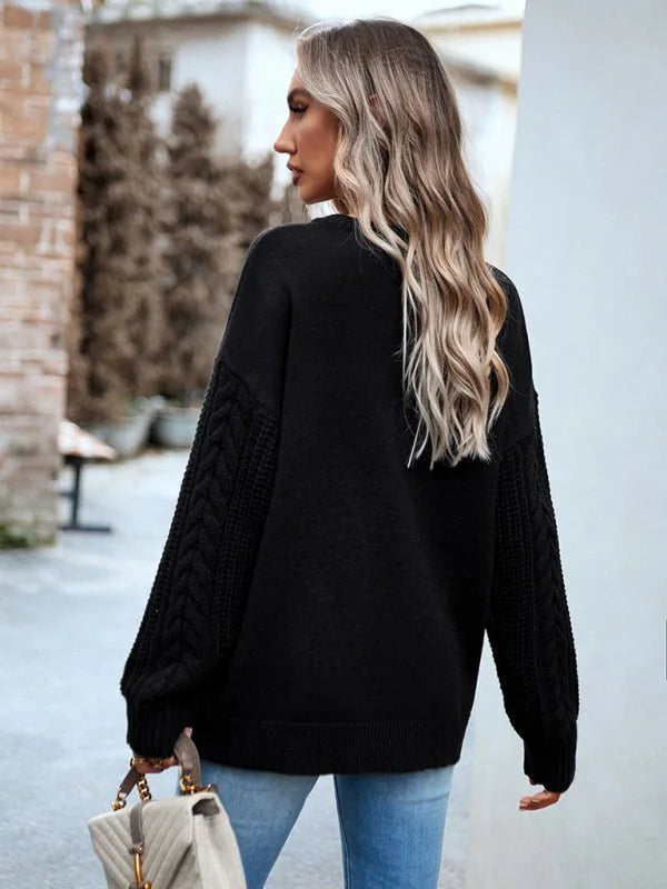 Black cable knit sweater with a relaxed fit, worn by a model from behind.