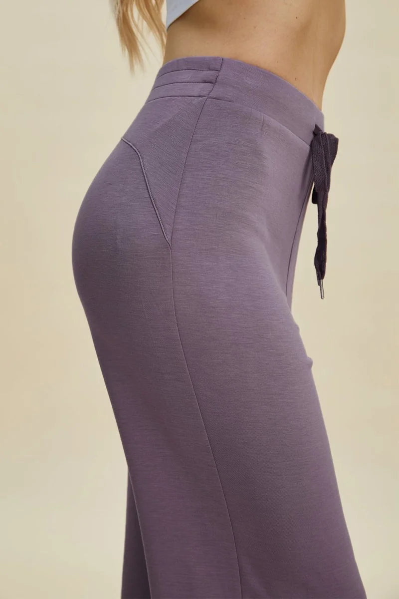 Close-up of dusty lavender pants with a drawstring waist and detailed stitching.