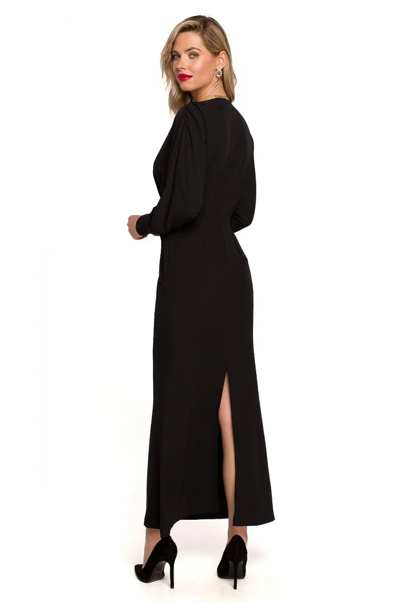 Black maxi dress with a high slit, long sleeves, and black stiletto heels on a white background.