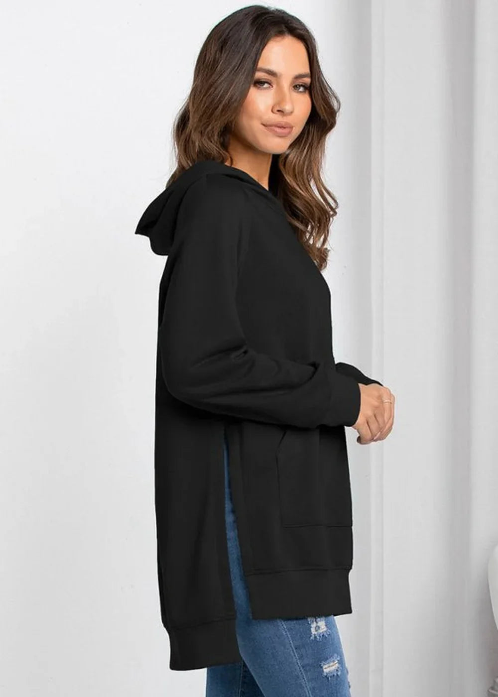 Black hooded sweatshirt with side slits, on a woman wearing ripped jeans.