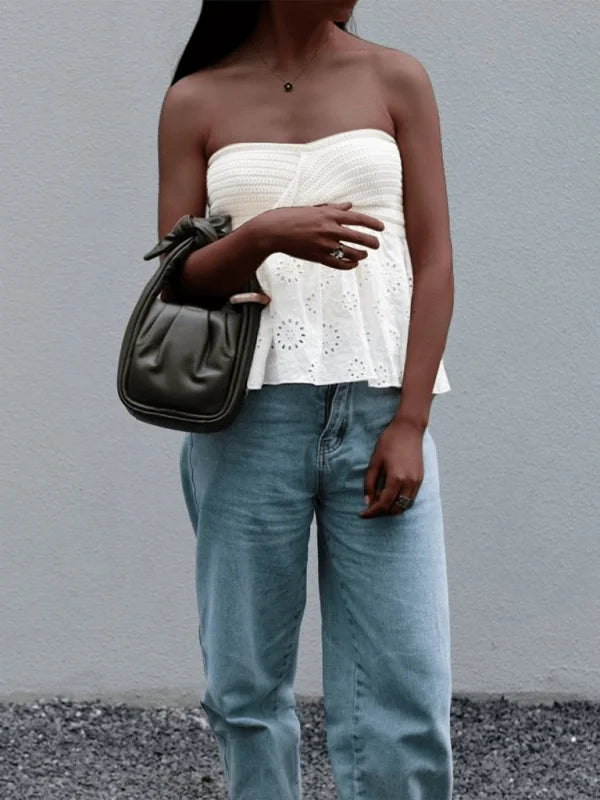 White crochet tube top with eyelet trim, paired with light wash denim jeans and a dark green handbag.