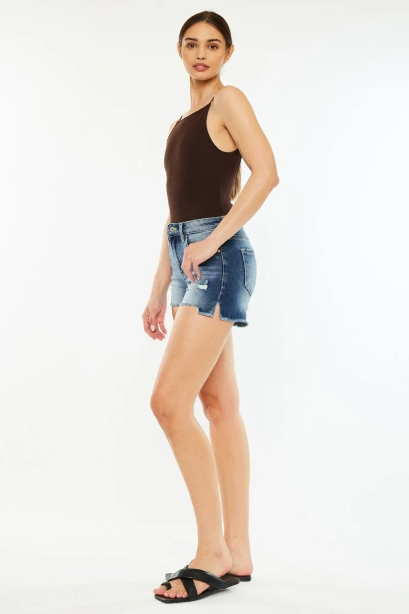 Distressed denim shorts with a frayed, split hem and a dark brown ribbed tank top on a model.