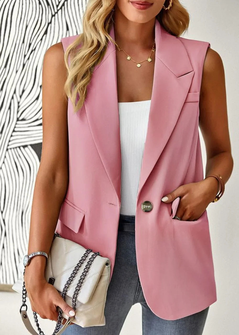 Pink sleeveless blazer with a button closure, worn by a model with a white top and jeans.