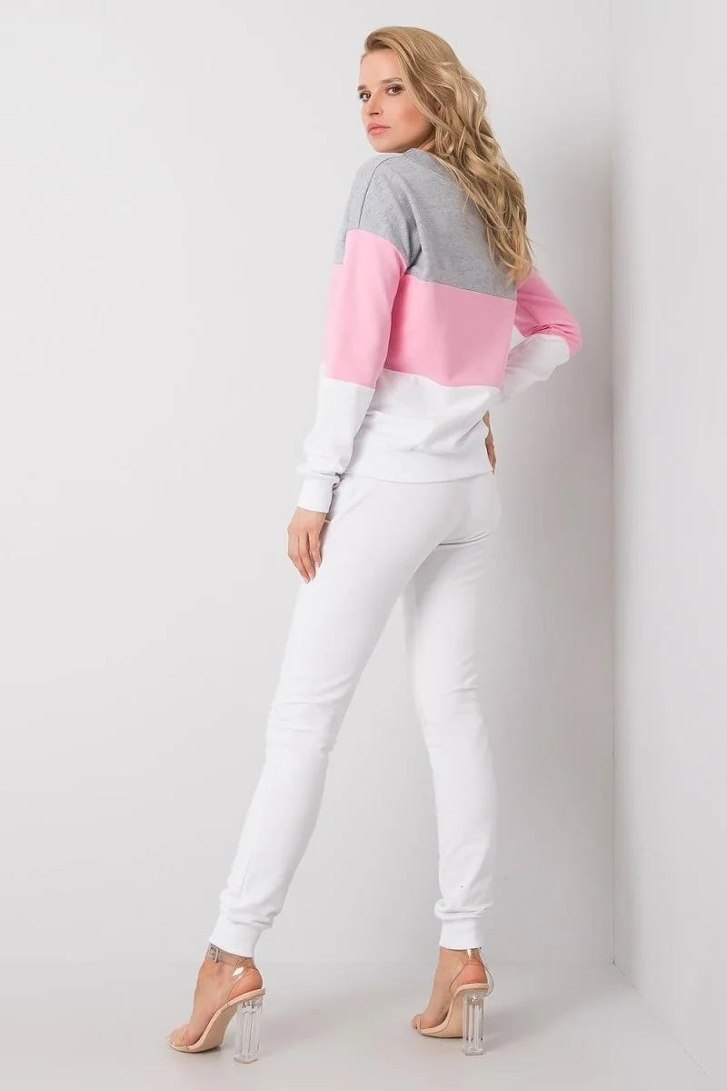 Woman in white sweatpants and a colorblock sweatshirt with pink, gray, and white sections, wearing clear heels.