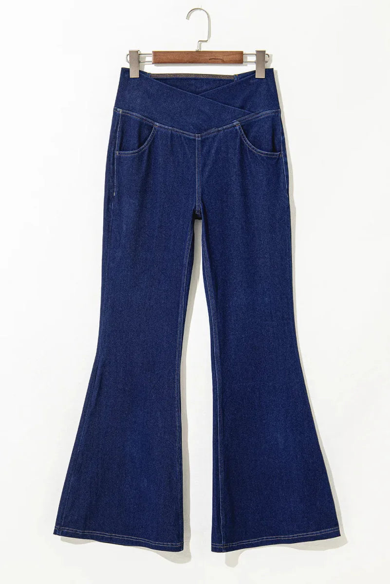 Dark wash denim flare pants with a criss-cross waistband and front pockets.