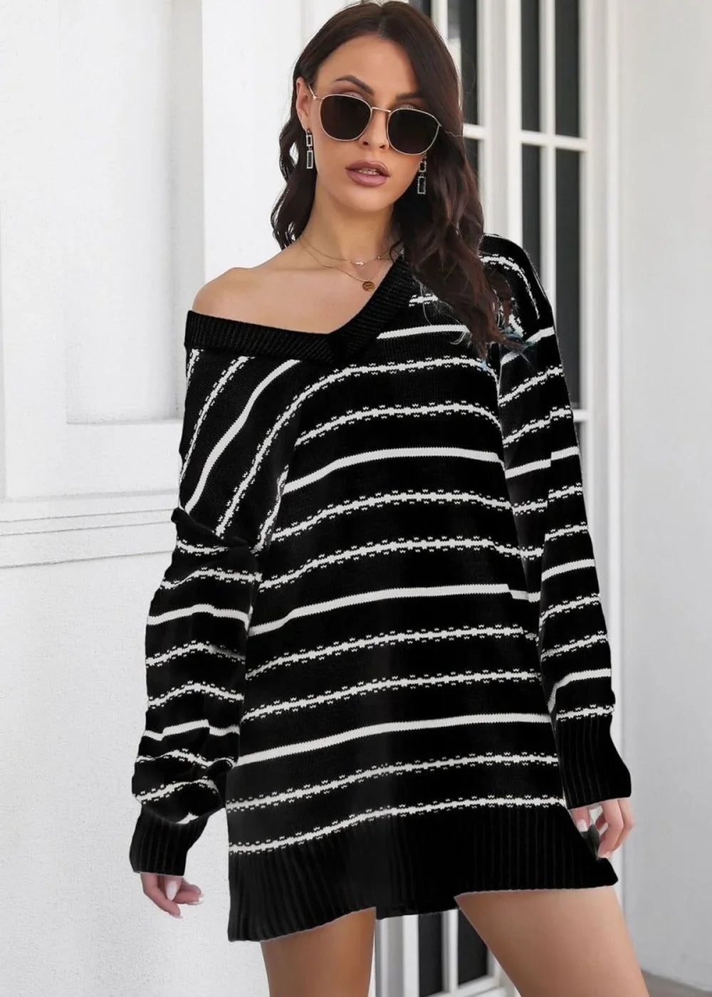Black and white striped sweater dress with a V-neck and off-the-shoulder style on a model.
