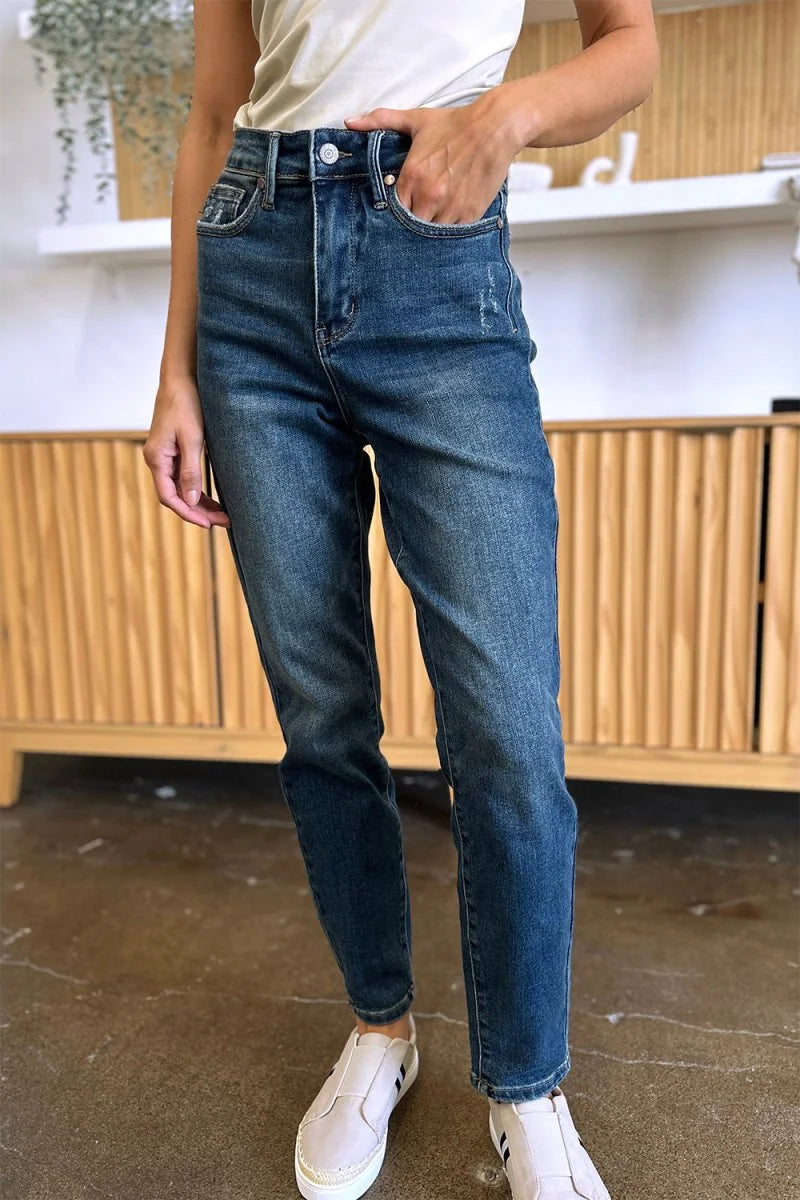 Distressed dark wash denim jeans with a relaxed fit and a button fly closure, shown on a model.
