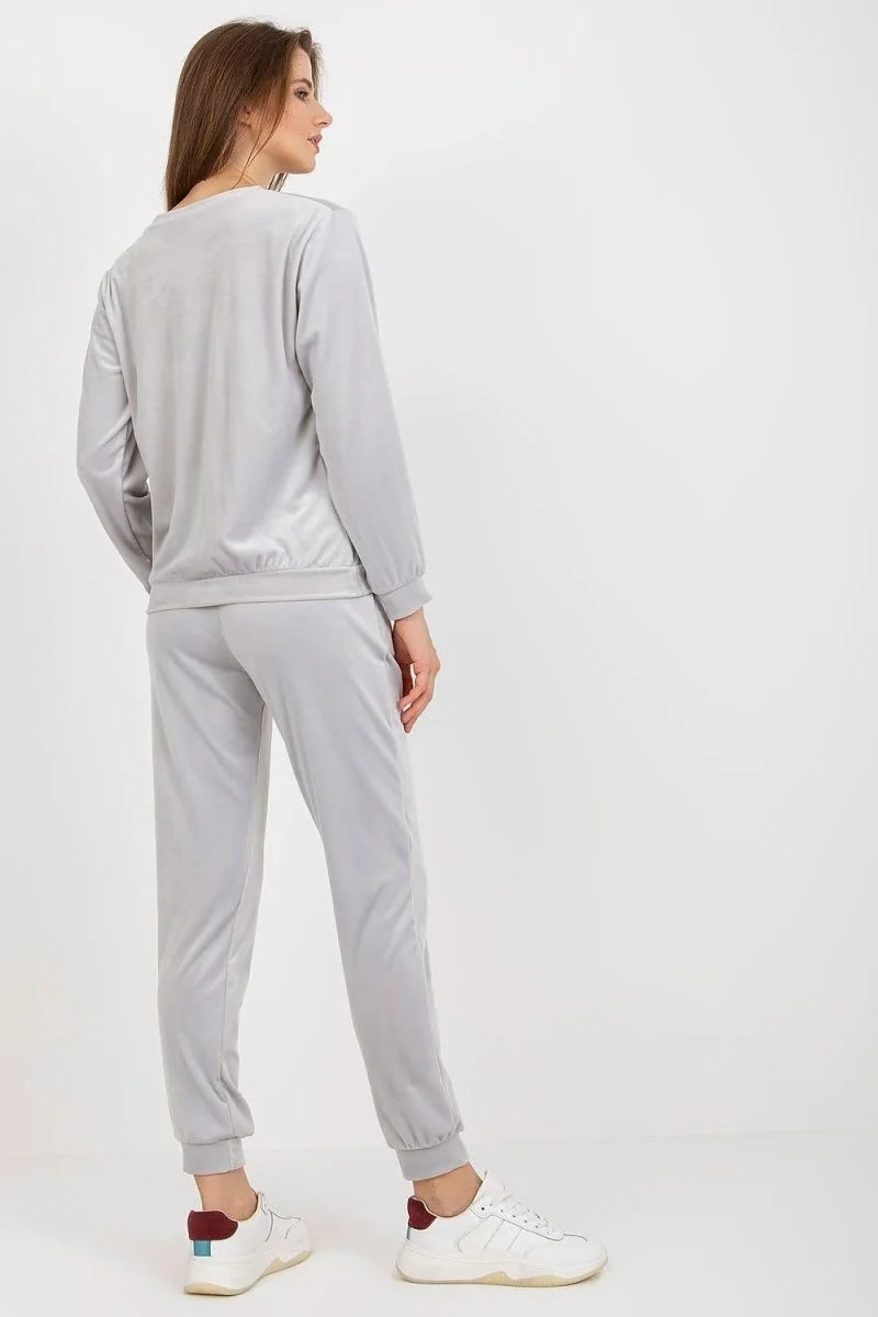 Light gray velour tracksuit with a crew neck sweatshirt and cuffed joggers, worn by a woman.