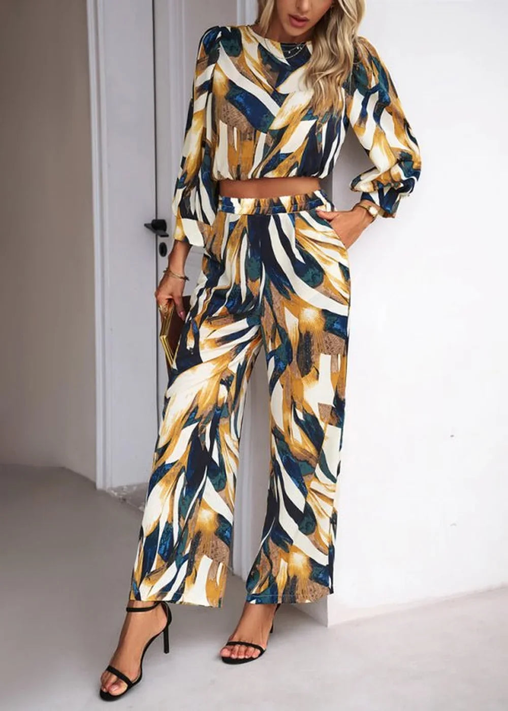 Woman wearing a flowing abstract print pant suit with wide-leg pants and a cropped long-sleeve top.