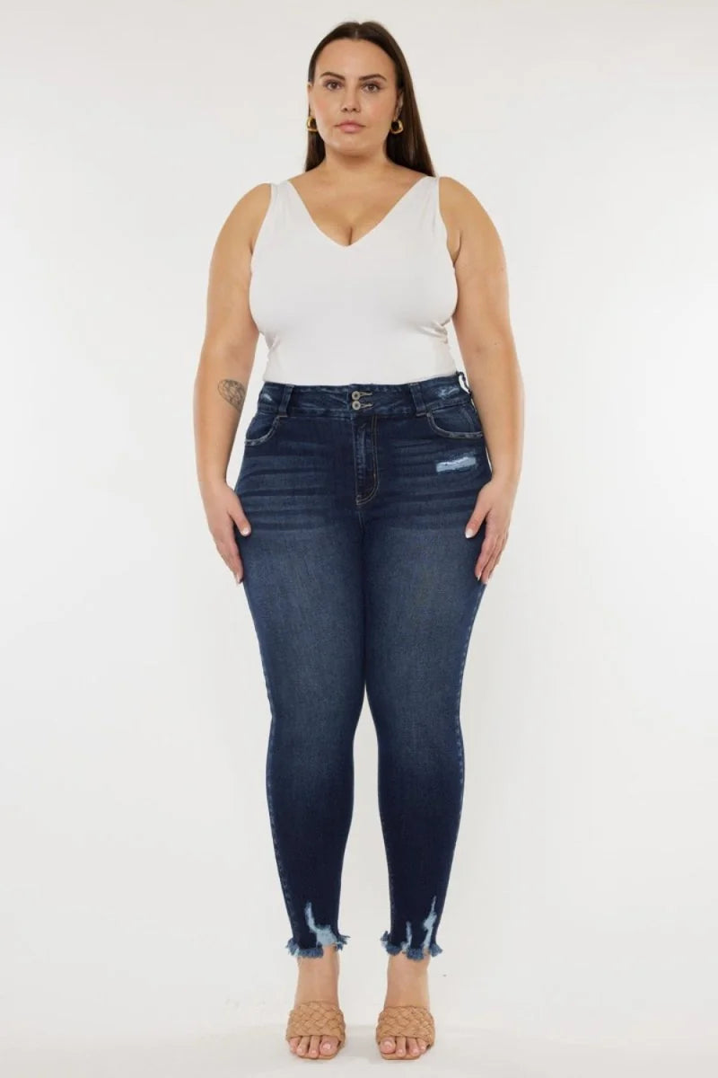 Dark wash denim jeans with a frayed hem and distressed accents, worn by a model.
