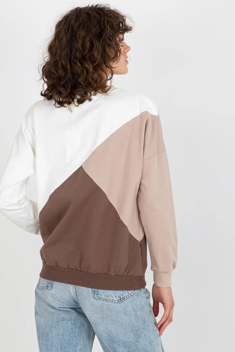Back view of a woman wearing a color-blocked sweatshirt in white, tan, and brown, with light blue jeans.