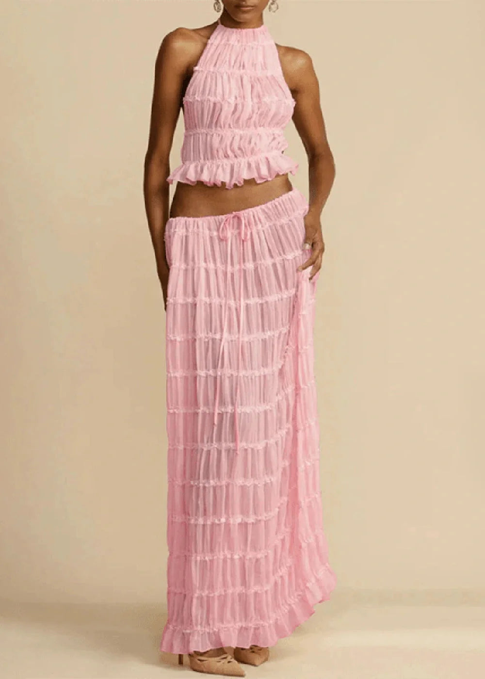 Pink ruched halter crop top and matching maxi skirt with drawstring waist on model.