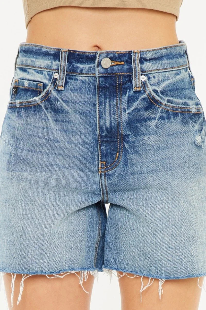 Close-up of distressed light blue denim shorts with a frayed hem and a gradient wash.