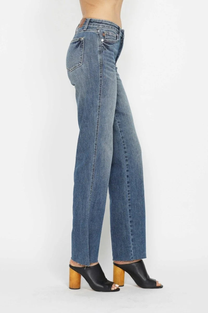 Medium wash straight leg jeans with frayed hem, paired with black open-toe mules.