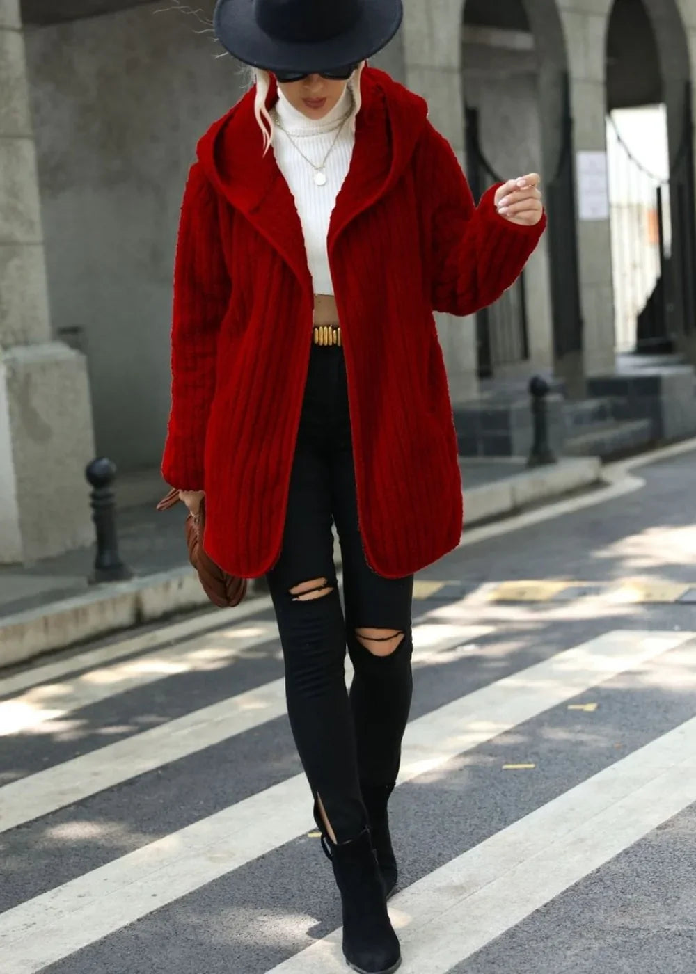 Red textured hooded cardigan with a white turtleneck and ripped black jeans on a model.